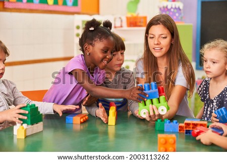 Children play together with building blocks in the international kindergarten with a kindergarten teacher Royalty-Free Stock Photo #2003113262