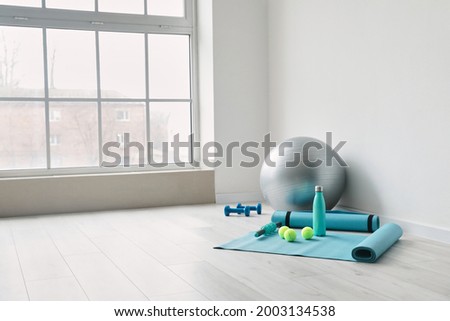 Set of sports equipment with fitness ball near light wall Royalty-Free Stock Photo #2003134538
