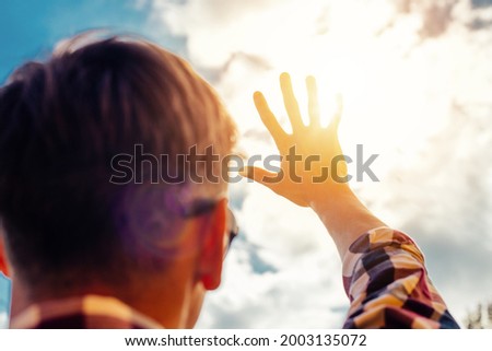 Man's hand covering sunlight, Sun shining through the hand, Human hand and sun Royalty-Free Stock Photo #2003135072