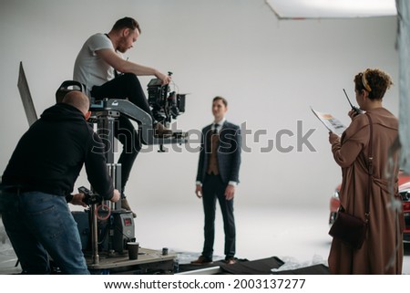 Carts, rails for filmmaking. Director of photography and engineer of movie camera trolley on set. Professional videographer on the set of a film, commercial or TV series. Filming indoors, studio