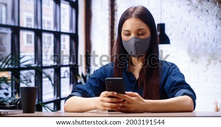 Portrait view of the focused young caucasian woman in headset with microphone sitting at the office, involved in video call conversation. Long haired girl having online meeting workshop with colleague