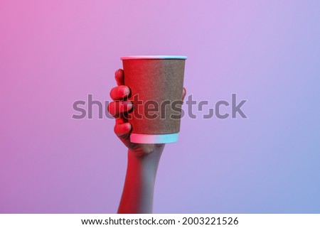 Paper cup in a woman's hand on a gradient background