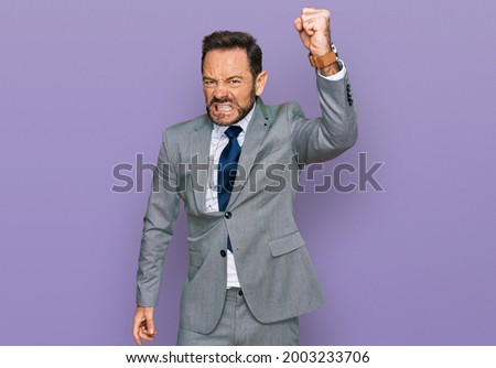 Middle age man wearing business clothes angry and mad raising fist frustrated and furious while shouting with anger. rage and aggressive concept.  Royalty-Free Stock Photo #2003233706