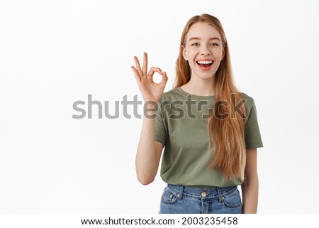 Very well. Laughing happy candid girl, showing okay OK sign and nod in approval, agree, like and praise something good, make compliment, recommend excellent product, standing over white background