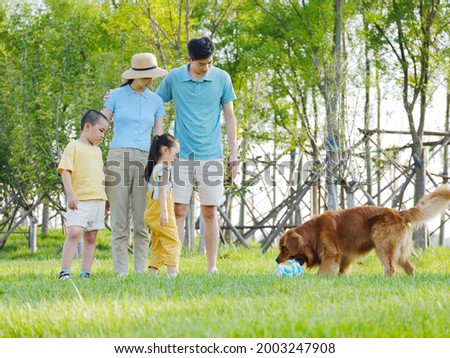 Happy family of four and pet dog playing in the park high quality photo