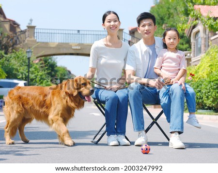 Happy family of three and pet dog playing outdoors high quality photo