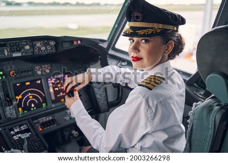 Lady pilot posing for the camera in the cockpit Royalty-Free Stock Photo #2003266298