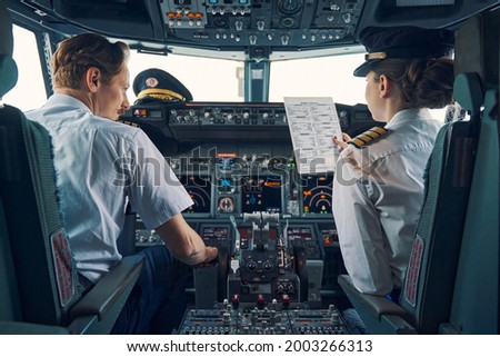 Pilot and female first officer seated in the flight deck Royalty-Free Stock Photo #2003266313