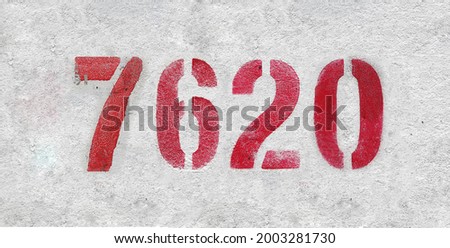 Red Number 7620 on the white wall. Spray paint. Number seven thousand six hundred and twenty.