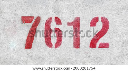 Red Number 7612 on the white wall. Spray paint. Number seven thousand six hundred and twelve.