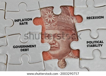 Part of the Malaysian Ringgit currency on jigsaw puzzle pieces. Four pieces of jigsaw puzzle there are words that are some of the key factors to the effect of foreign exchange rates.