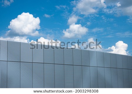 gray background and blue background. in the photo, a gray metal wall against a blue sky with clouds