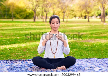 Latin woman performing Reiki poses in a park