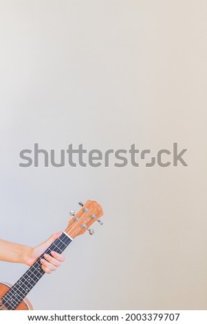 Young woman's hand holding an ukulele.