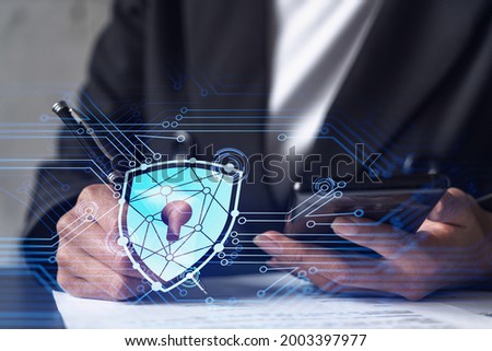 Businesswoman in formal wear signing the contract to prevent probability of risks in cyber security. Checking the phone. Padlock Hologram icons over the working desk.