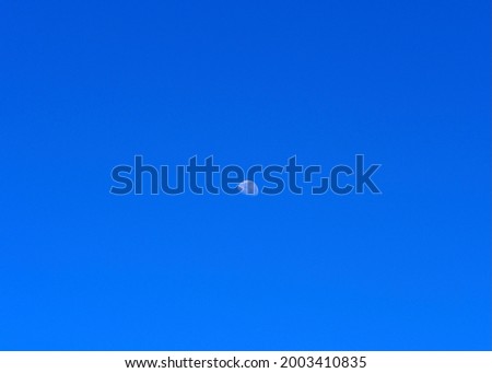 Moon visible during the day against a clear blue sky