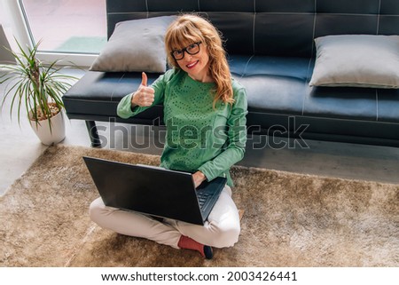 woman at home with computer and sign of satisfaction and approval