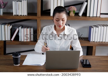 Asian manger businesswoman or secretary operator is writing and working with laptop at office. Collegian is studying knowledge in library at the university. Business and education with technology. Royalty-Free Stock Photo #2003438993