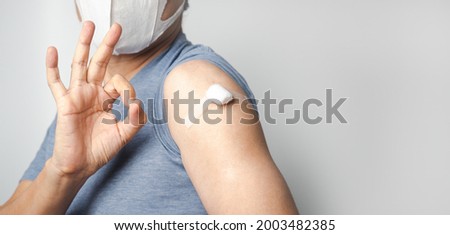 Asian man doing ok sign with fingers and show cotton after make injection Covid-19 or Coronavirus vaccination immunity on his arm