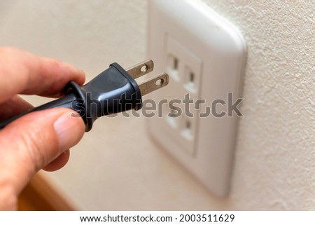Connect the power plug to the electric outlet on the wall Royalty-Free Stock Photo #2003511629