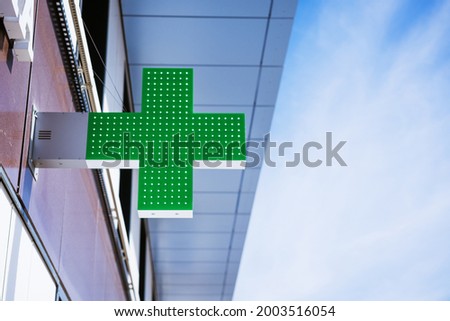 green cross on the facade of the building against the sky