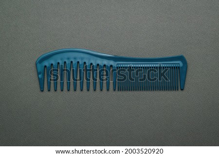 Blue plastic comb for combing hair on a dark gray background. A tool for hair care. Flat lay.