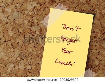 Yellow note on cork board with message DON'T FORGET YOUR LUNCH! , to remind hard worker or a workaholic to take a break and find work life balance Royalty-Free Stock Photo #2003529302