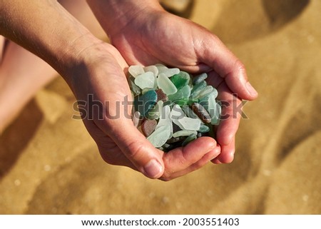 Cupped hands hold sea glass collected from the beach Royalty-Free Stock Photo #2003551403