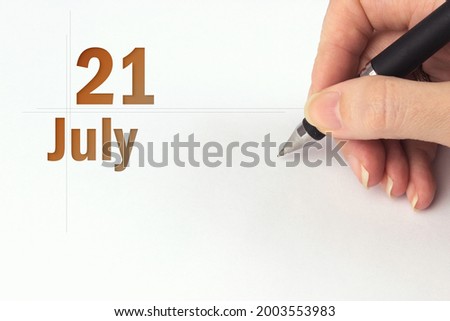 July 21st . Day 21 of month, Calendar date. The hand holds a black pen and writes the calendar date. Summer month, day of the year concept