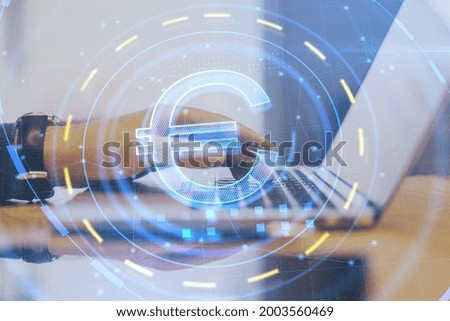 Side view of businessman hands using laptop with glowing euro sign at blurry desktop. Investment, online banking and trade concept. Double exposure
