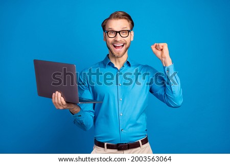 Photo of young business man happy positive smile use laptop rejoice victory fists hand isolated over blue color background