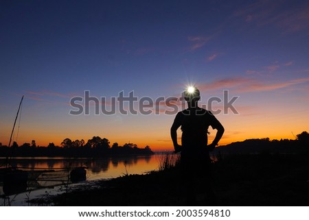 A trail runner standing with a headlamp on his head with silhouette sky Royalty-Free Stock Photo #2003594810