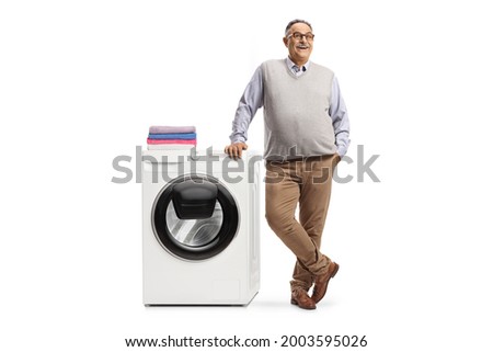 Smiling mature man leaning on a washing machine isolated on white background