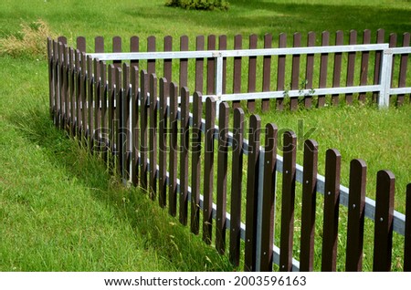 low fence, as protection against dogs. protects the playground from uninvited guests. The fence planks are made of recycled plastic and look almost like wood Royalty-Free Stock Photo #2003596163