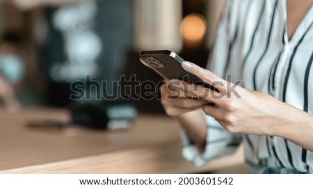 Close up hand of woman using smartphone at coffee shop cafe Royalty-Free Stock Photo #2003601542