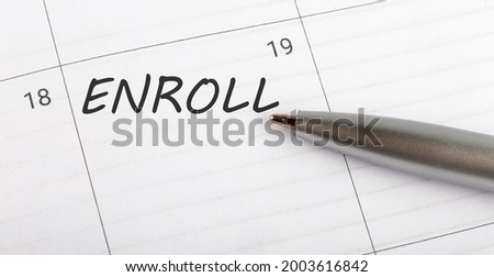 Text ENROLL on calendar planner to remind you an important appointment with a pen on the isolated white background.