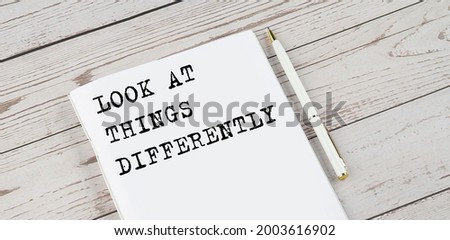 Notepad with text LOOK AT THING DIFFERENTLY . White background. Business