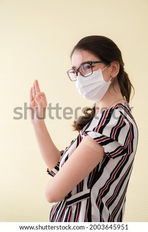 Young women wearing masks standing show plaster bandage at the shoulder make a mark hand sign OK. After vaccine protection coronavirus 19 for immunization. Concepts to prevent the spread of COVID-19.
