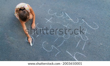 The child is doing chalk lessons on the asphalt. Selective focus. Kid.