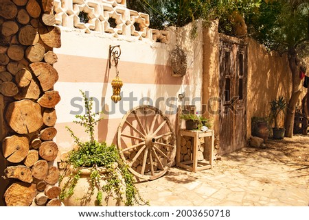 Ethnic style patio with oriental touches, large wooden wheel and potted plants. Afternoon siesta in the sun-drenched courtyard. Authentic ethnic courtyard concept
