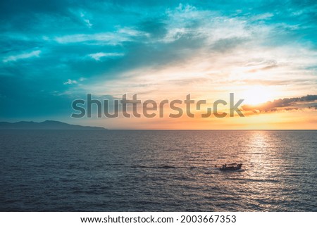 Amazing colorful sky sunrise above mountains and deep blue ocean with fishing boat