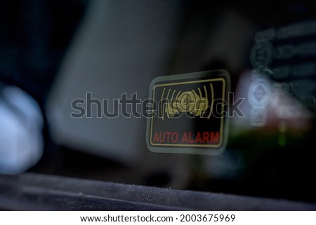 Close up shot of car auto alarm system symbol sticker indicate the active stolen car emergency alarm security system on the side-facing window on a vehicle