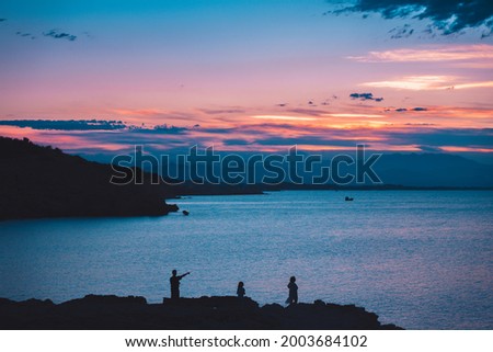 Silhouette of family looking a scenic view of the sun reflecting on a calm ocean. Colorful sky sunrise.