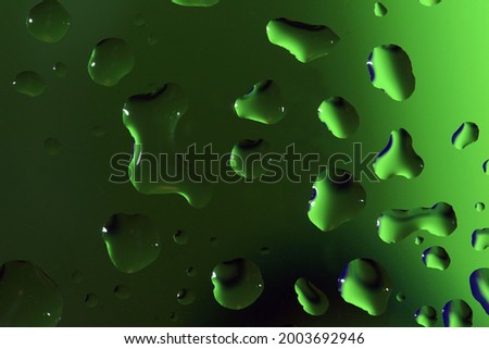                  water drops on a glass with colorful green background              
