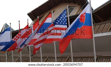 Many national flags of different states hang and blowing on building. Worldwide. International Flags are flying on building. American, Thai, Croatian, Slovak, Canadian, Israeli Flags.