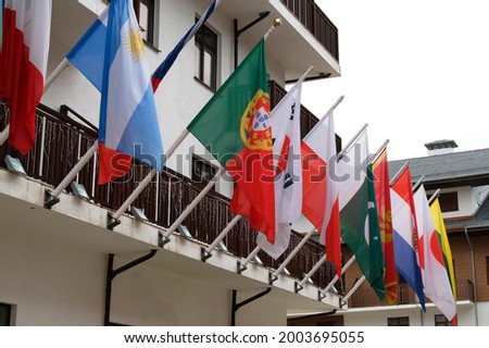 Many national flags of different states hang and blowing on building. Worldwide. International Flags are flying on building. Portuguese, Argentinean, Polish, South Korean, Pakistani Flags.