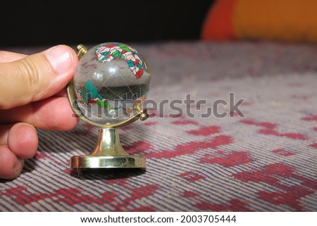 A small glass globe on a stand in his hand