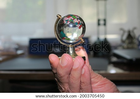A small glass globe on a stand in his hand