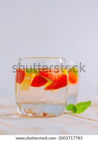 strawberry-citrus homemade summer refreshing drink. lemon water with berries in a glass on the table.