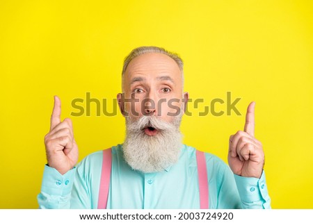 Photo of impressed mature man point up wear blue shirt isolated on vivid yellow color background